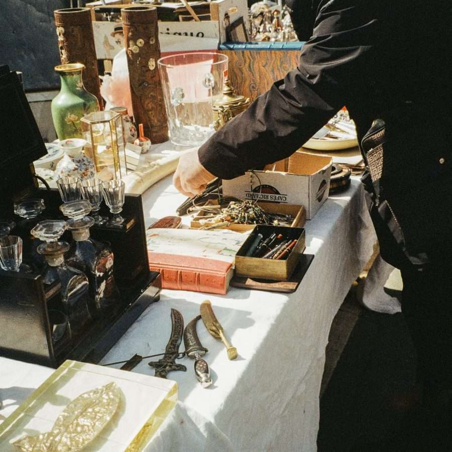 a man standing over a table filled with antiques