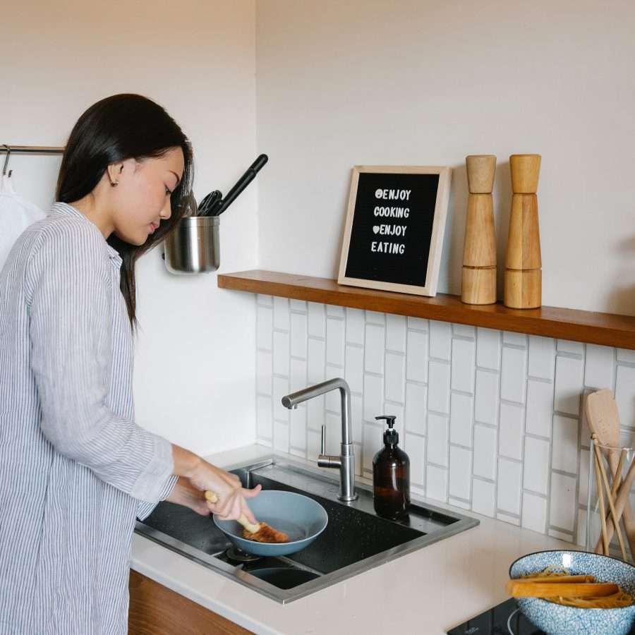  an Asian woman washing dishes using a boiling water tap