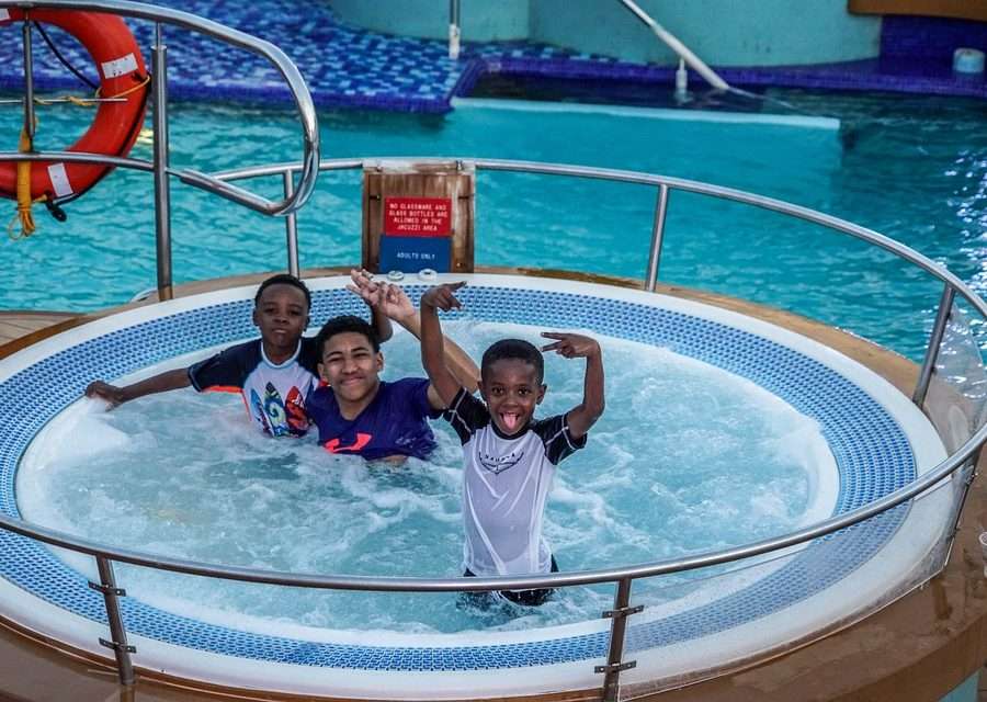  three boys posing inside a hot tub