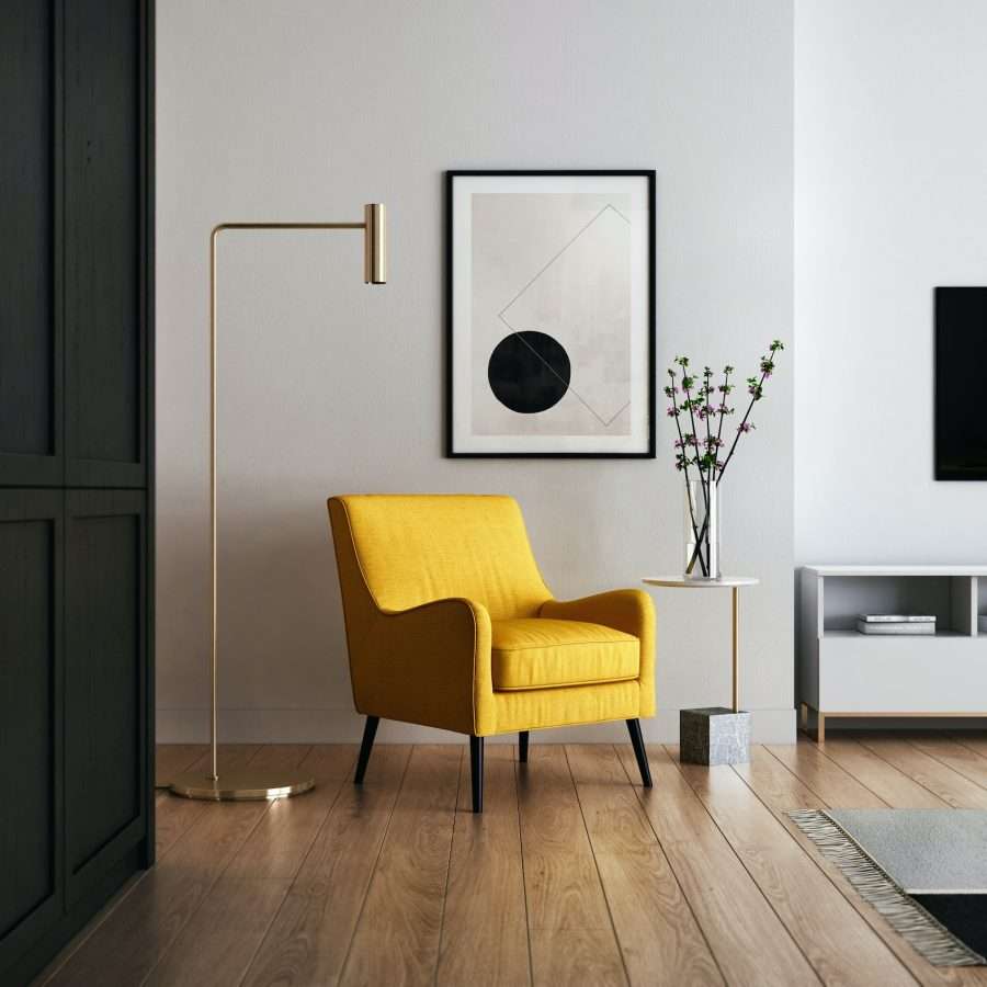 a brown wooden framed yellow padded chair beside an artwork