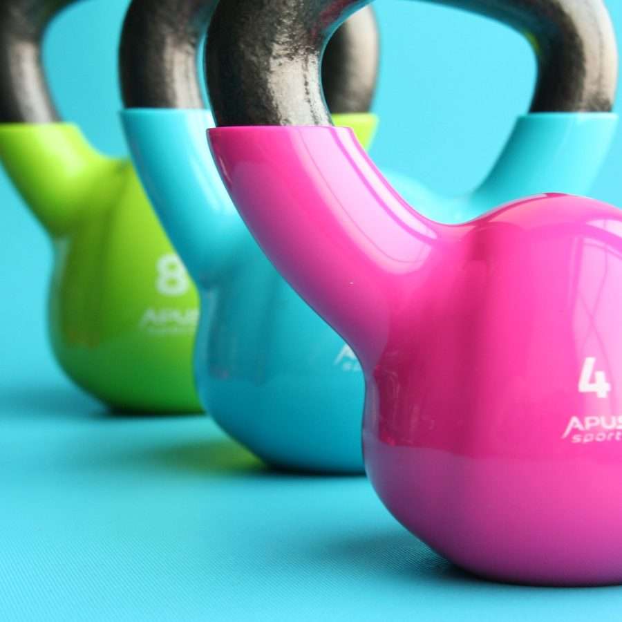 Green, Blue, and Pink Kettle Bells on Blue Surface